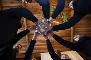 Wedding party members performing a synchronized dance move on a wooden floor.