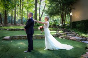 Bride and groom participate in first look moment in garden setting.