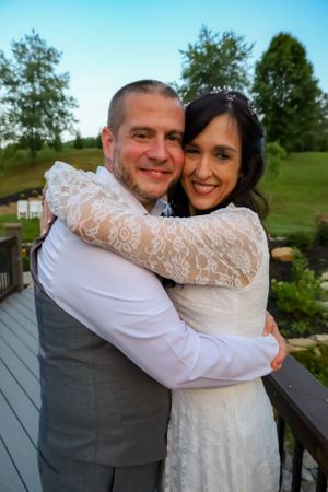 A couple shares joyful embraces on an outdoor deck during their wedding celebration.