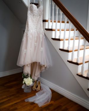 White wedding dress and shoes arranged on wooden stairs in natural light.