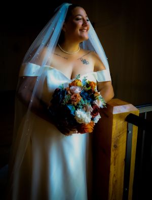 Colorful bridal bouquet with vibrant flowers contrasts against white wedding dress.