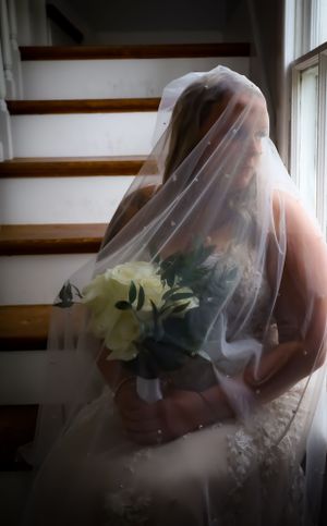 Close-up shot of a bride wearing a delicate veil with white flowers in soft window light.