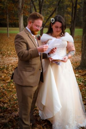 A couple checks their phones during a casual moment at their outdoor wedding.
