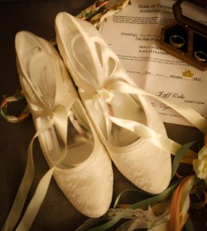 White ballet slippers arranged with wedding documents in soft lighting.