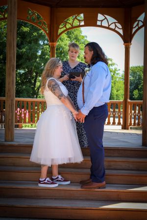 Children in formal attire playing on wooden gazebo steps during a wedding celebration.