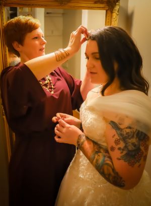 A couple dances together during a wedding celebration, with the bride wearing a white dress with visible tattoos.