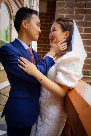 Intimate wedding portrait of couple against brick wall showing tender affection.