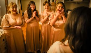 Wedding party members in peach-colored dresses sharing an emotional moment.