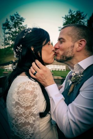 Intimate wedding portrait with teal background showing couple in lace dress and gray vest.