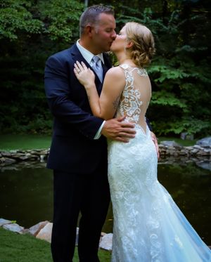 A romantic wedding photo series showing a couple kissing by a stream in a lush forest setting.