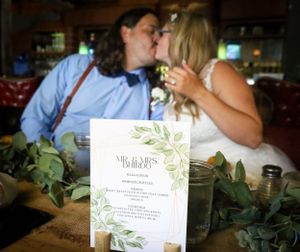 Wedding reception table details with floral menu cards and greenery decorations.