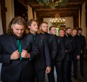 Wedding party members in black attire posing in an elegantly lit indoor venue.