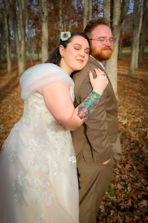 A couple embraces lovingly among fallen leaves during their autumn wedding photoshoot.