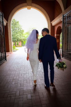 A couple walks through an arched hallway after their wedding ceremony.