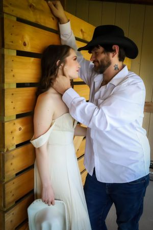 A romantic moment captured in a rustic barn setting with soft natural lighting.