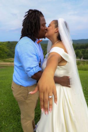 Romantic outdoor wedding moment captured against rolling hills and blue sky.