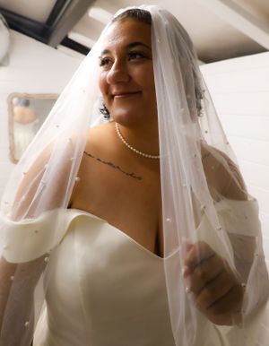 Bride wearing pearl necklace and veil in elegant getting ready portraits.