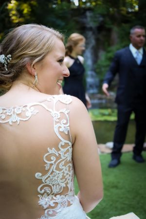 Detail shot of intricate lace back wedding dress design in outdoor setting.