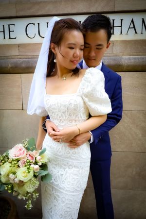 Elegant bride in lace dress holds bouquet while sharing intimate moment with groom at The Cunningham.