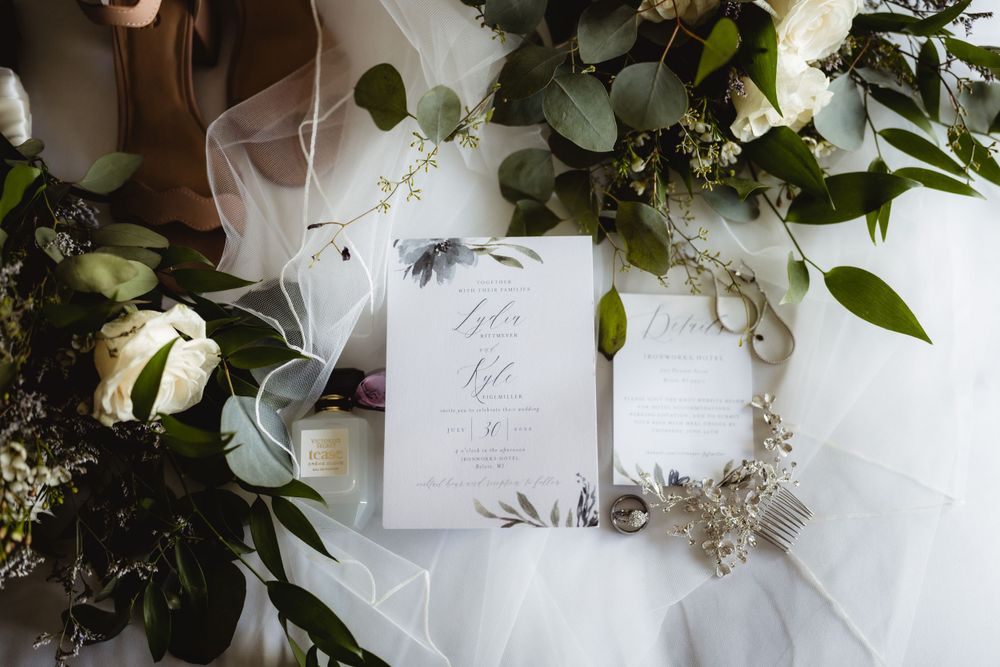 Elegant wedding invitation details with white veil and greenery arrangements.