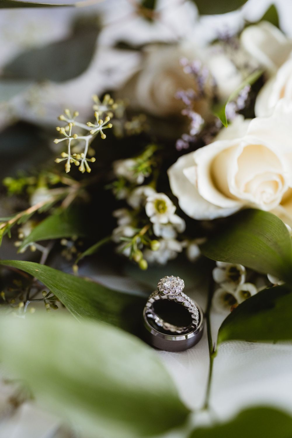 Diamond engagement ring nestled among white roses and delicate floral arrangements.