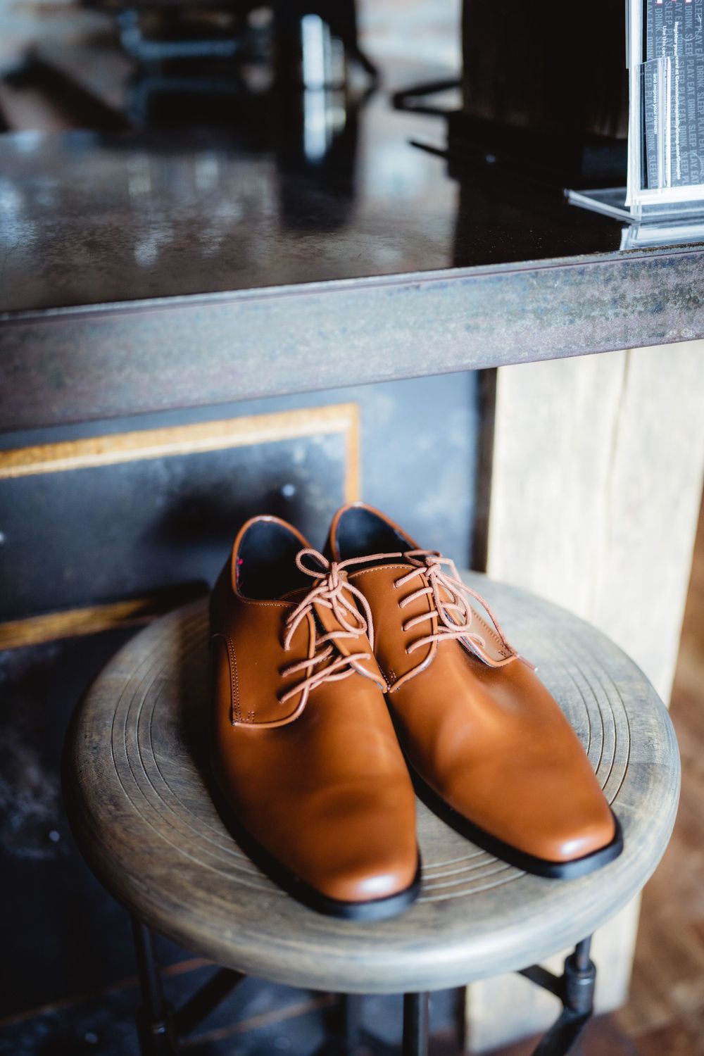 Brown leather dress shoes displayed on a dark wooden pedestal.