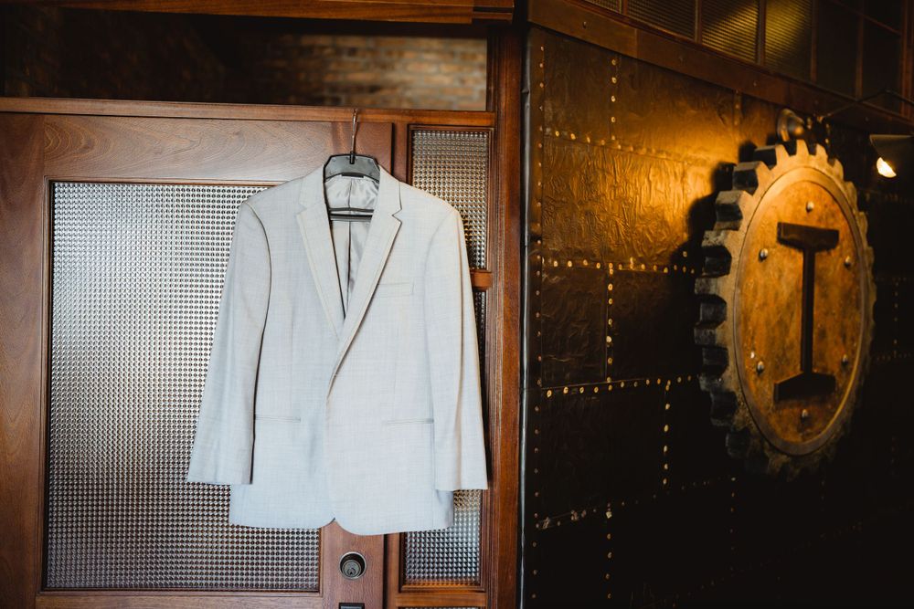 White suit jacket hanging in an elegant wooden wardrobe.