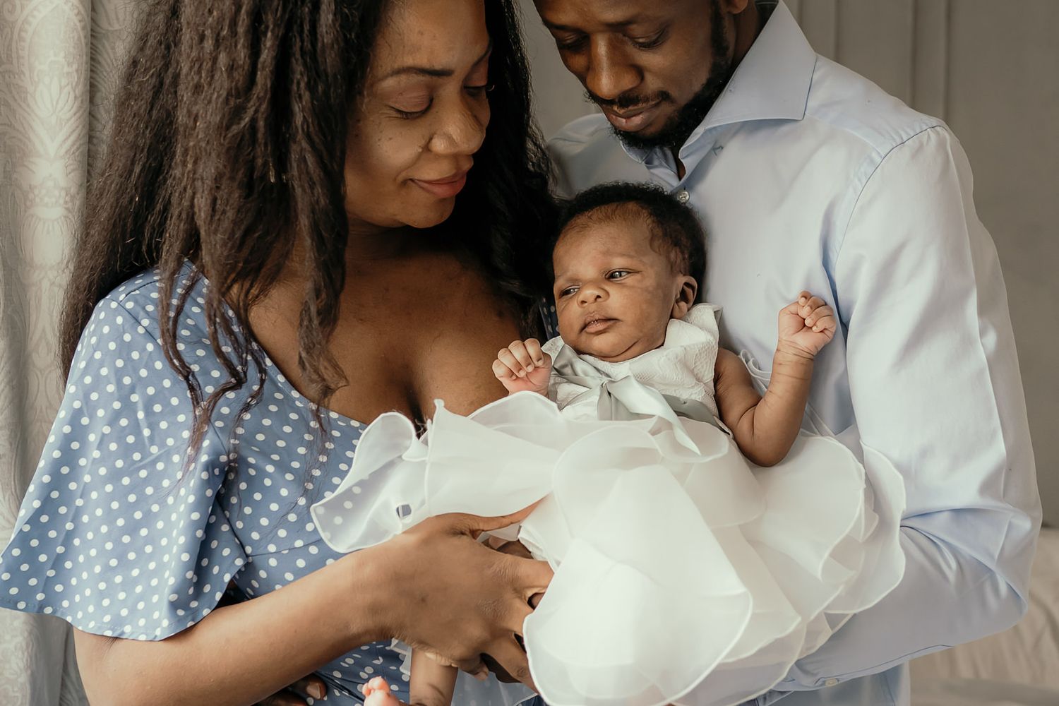 Mother and father cradling their newborn baby girl whilst looking down at her