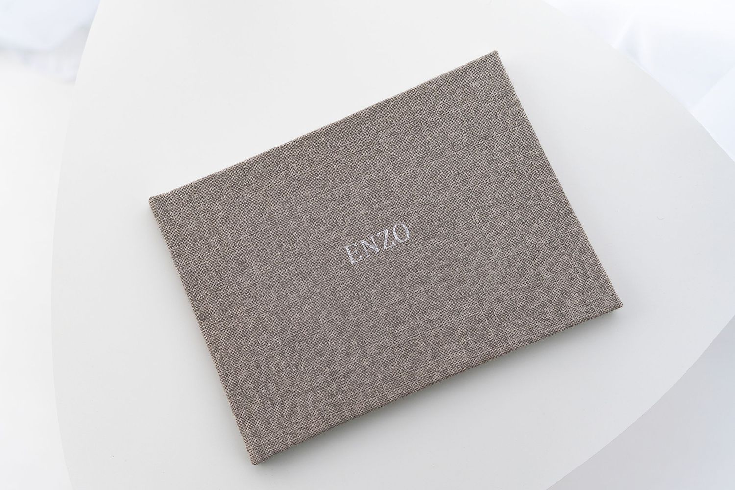 Gray linen photo album book displayed on white surface.