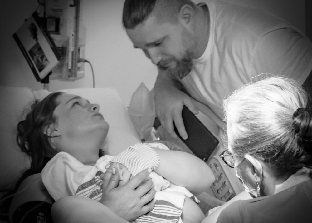 Emotional black and white capture of first moments with newborn in delivery room.