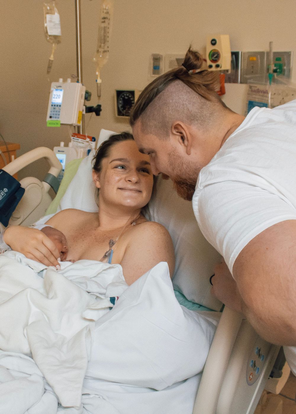 Emotional moment in hospital room as couple shares intimate moment after delivery.