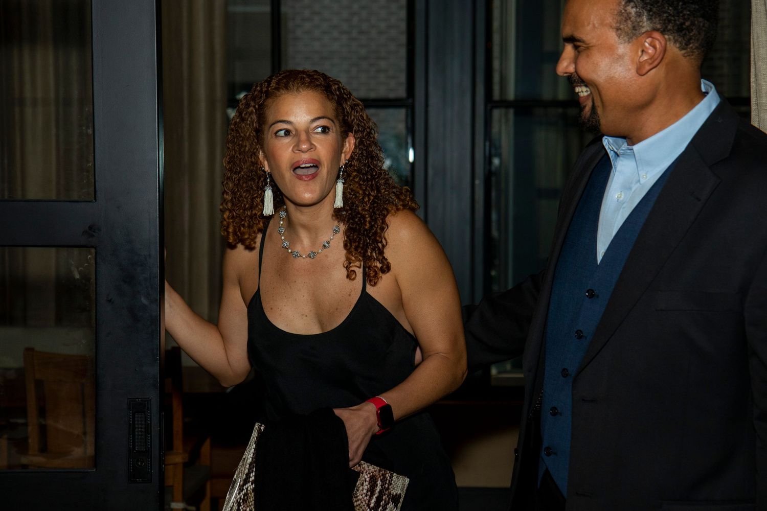 A candid nighttime photo of people laughing outside a building entrance.
