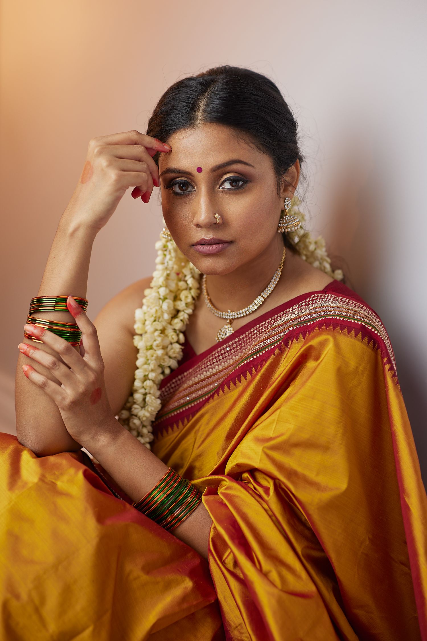 Portrait of woman in yellow silk sari with traditional South Indian jewelry and flowers.
