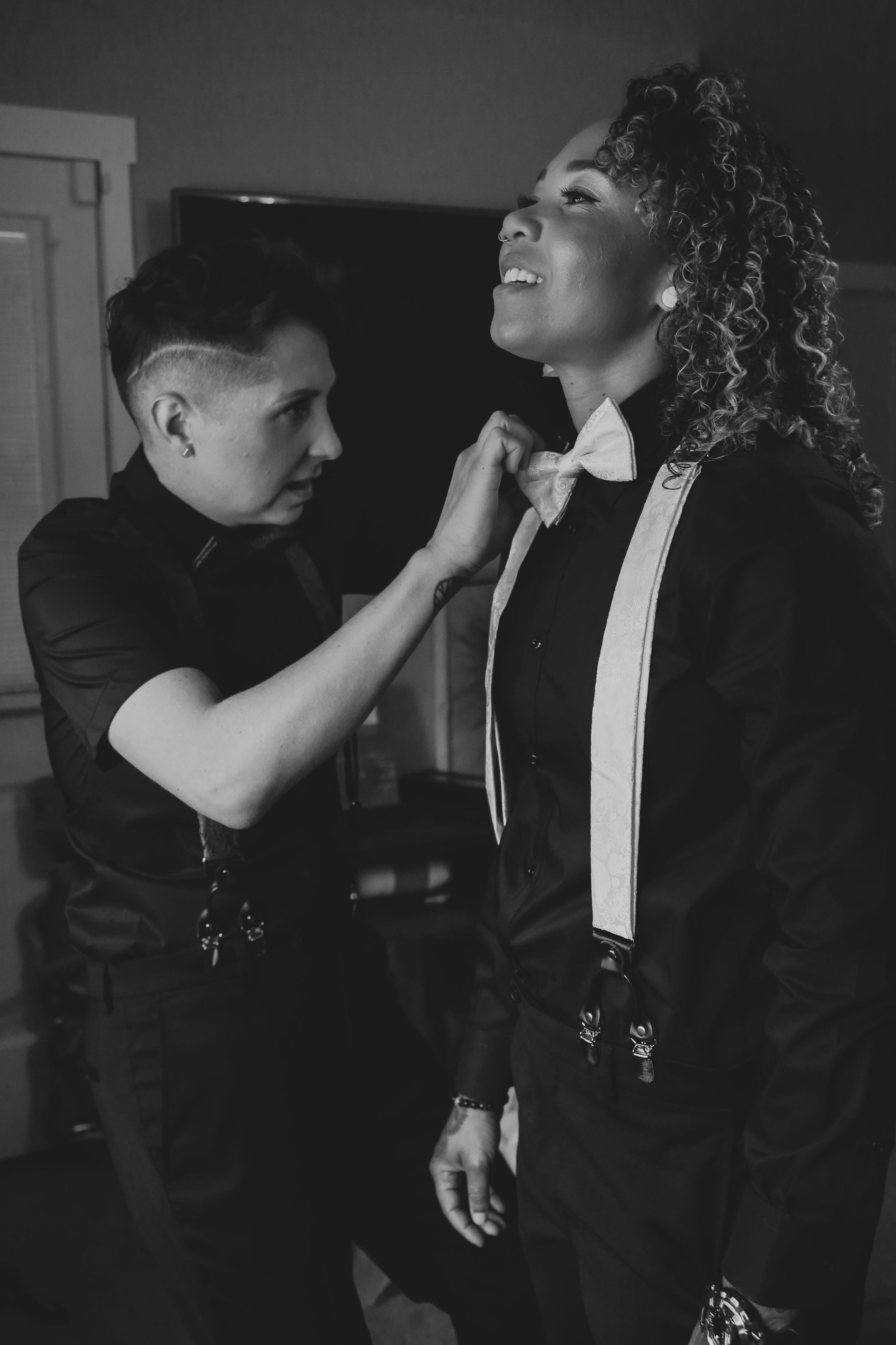 People adjusting bow ties in formal black attire.