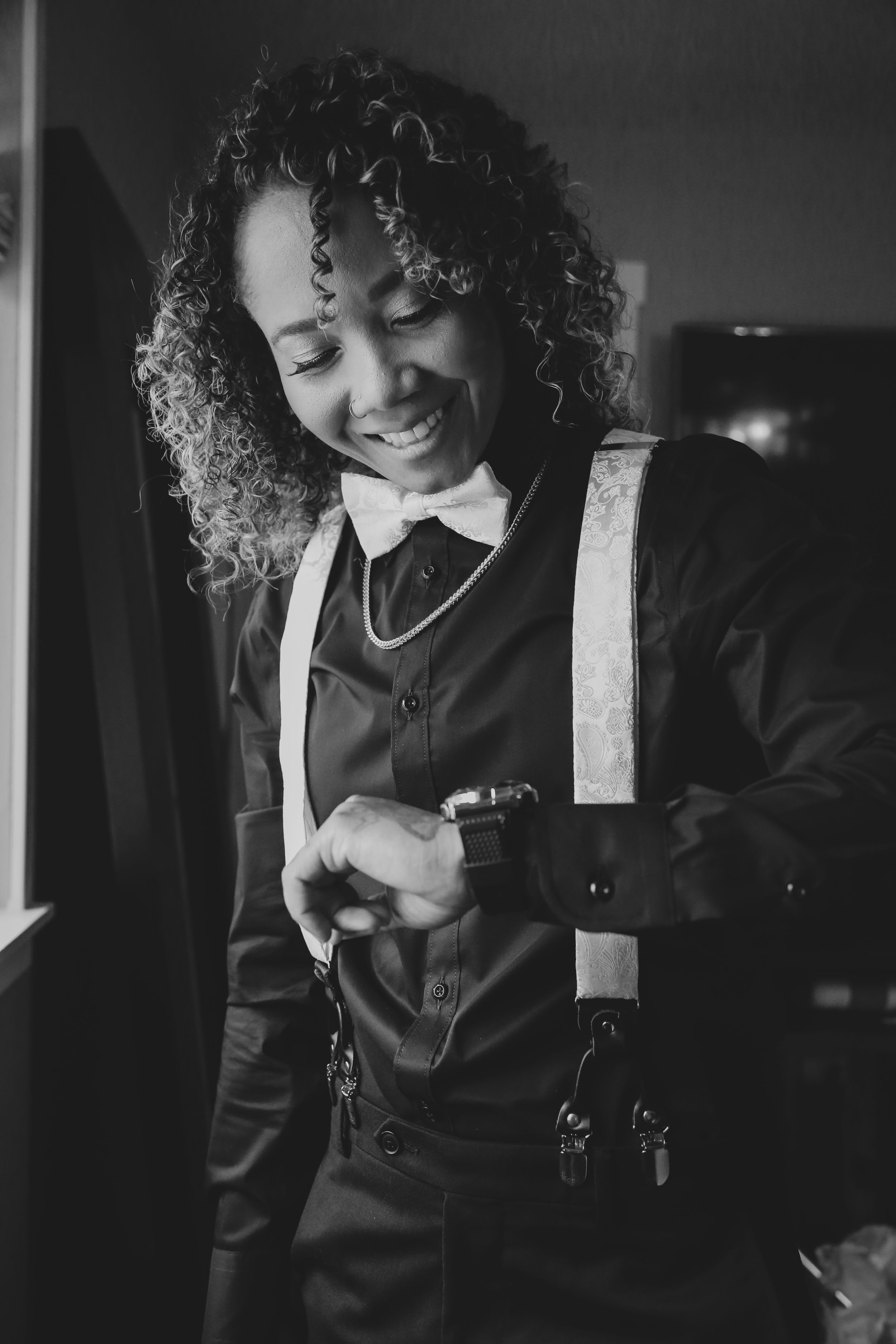 Person in black formal wear with curly hair smiling.