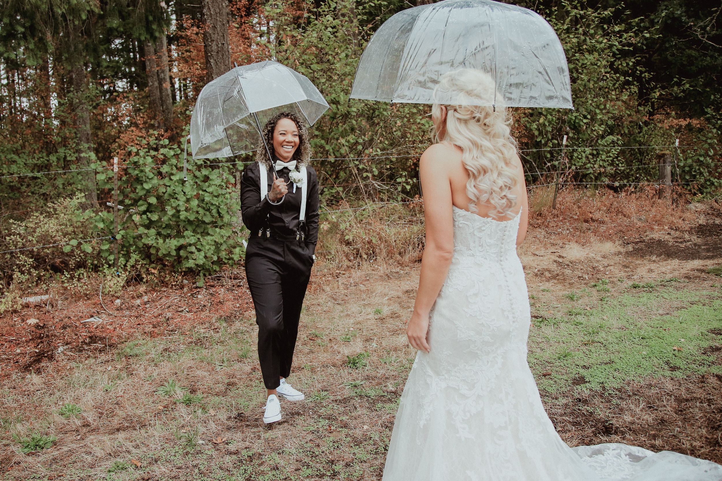 Wedding couple posing with clear umbrellas among trees.