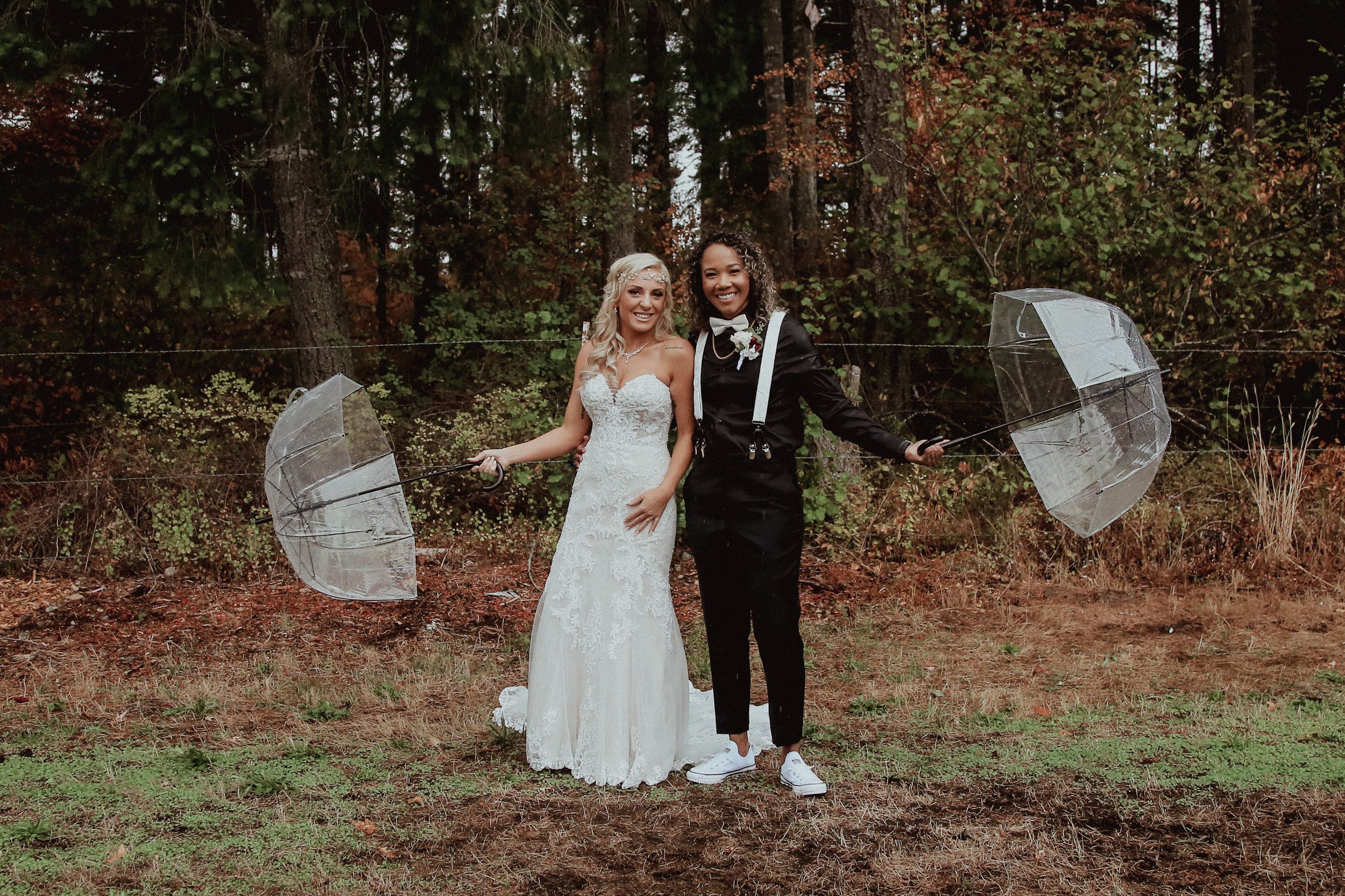 Couple in wedding attire walking through an autumn forest setting.