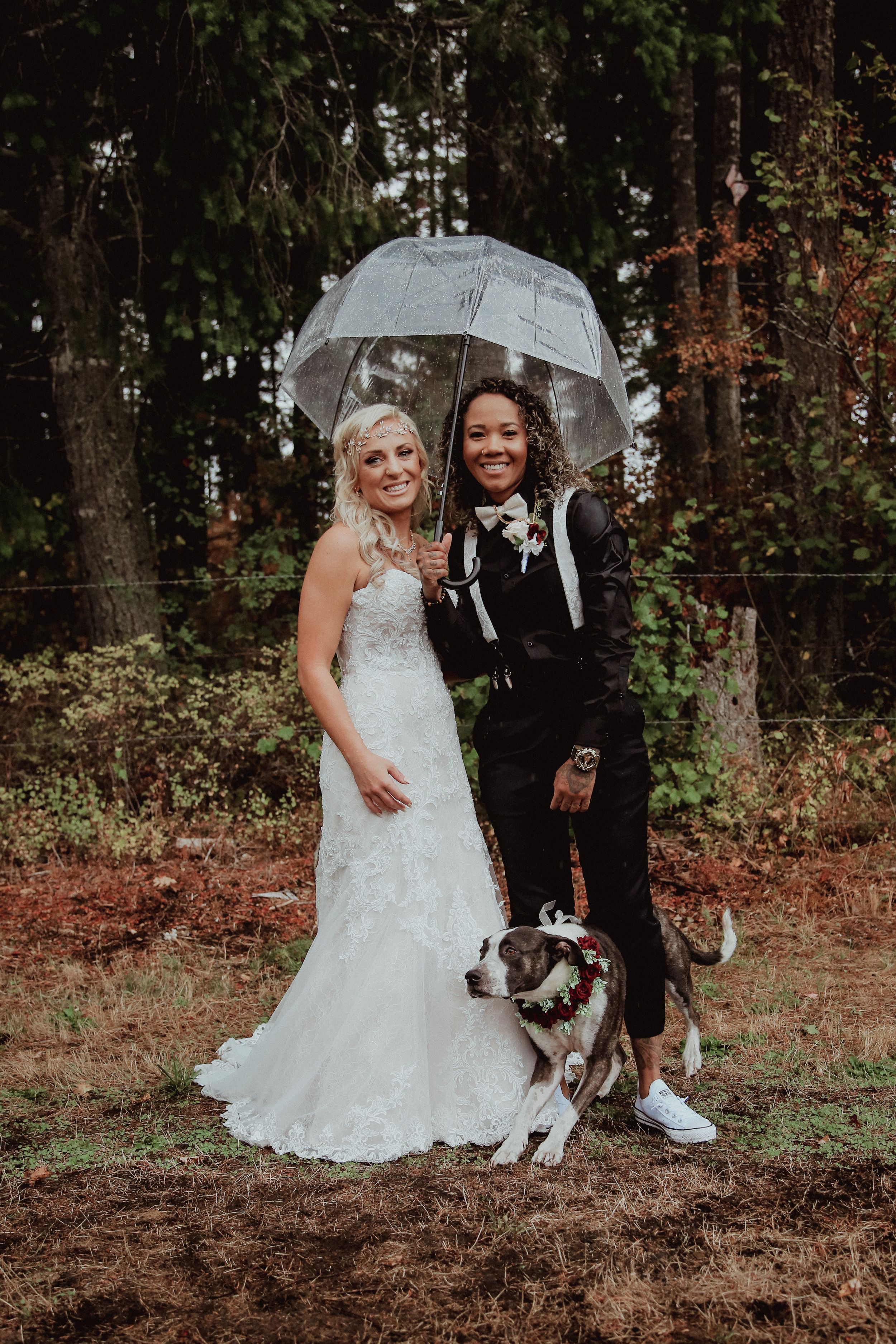 Wedding couple with clear umbrellas posing in a wooded area.