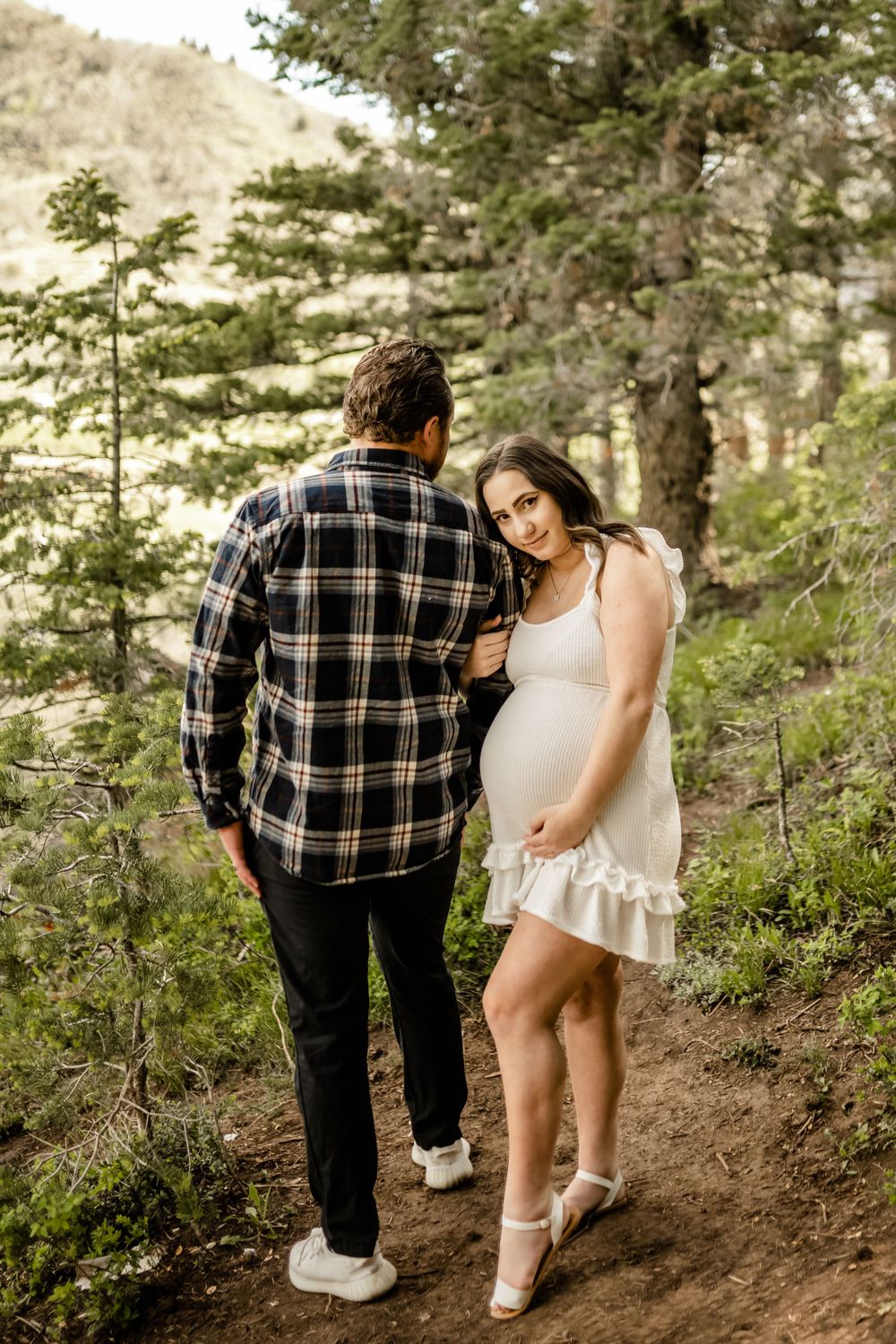 A couple explores a wooded hiking trail while wearing casual outdoor attire.