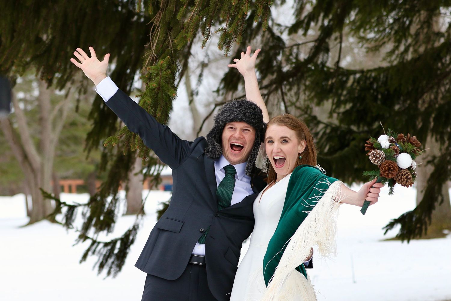 This image is a young couple celebrating their marriage in the snow!  They look happy, celebrating with arms spread wide