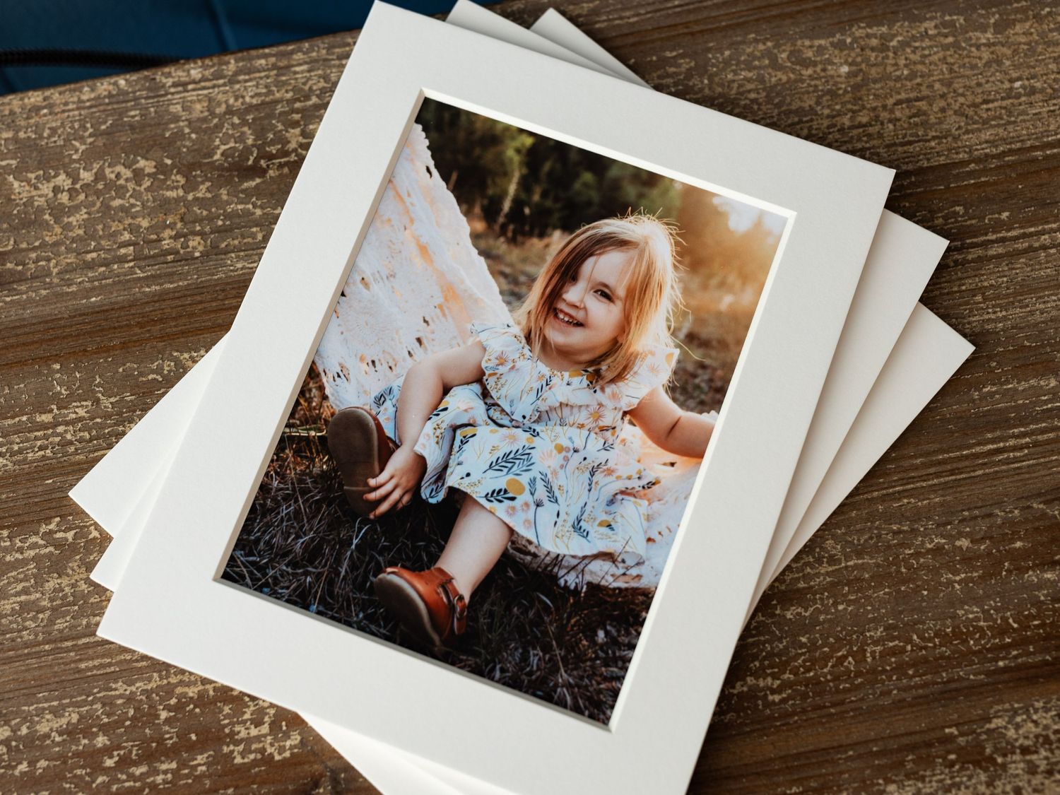 A stack of white-bordered professional photos on a wooden surface.