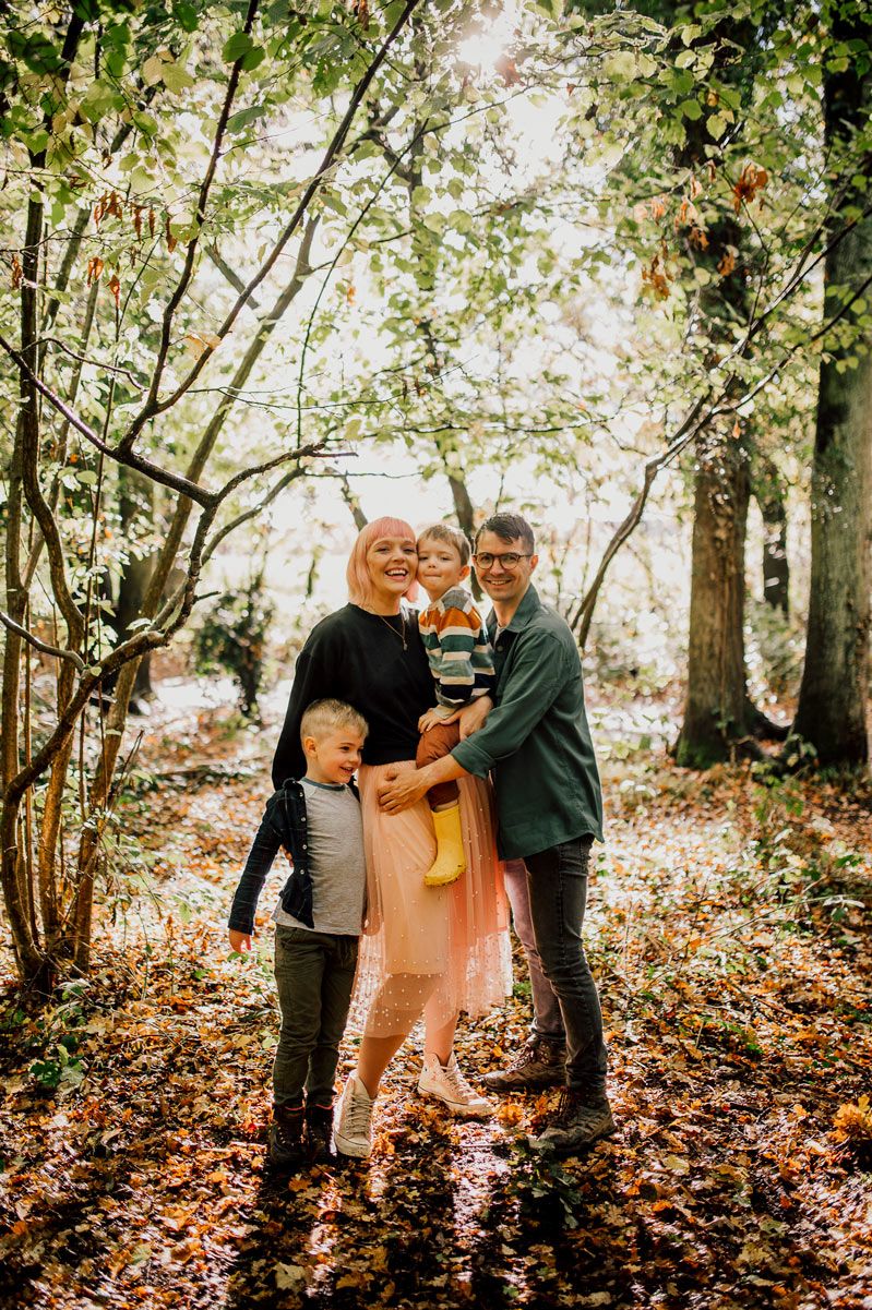 Family gathering in autumn woods with fallen leaves covering the ground. Worcestershire Wedding photographer.