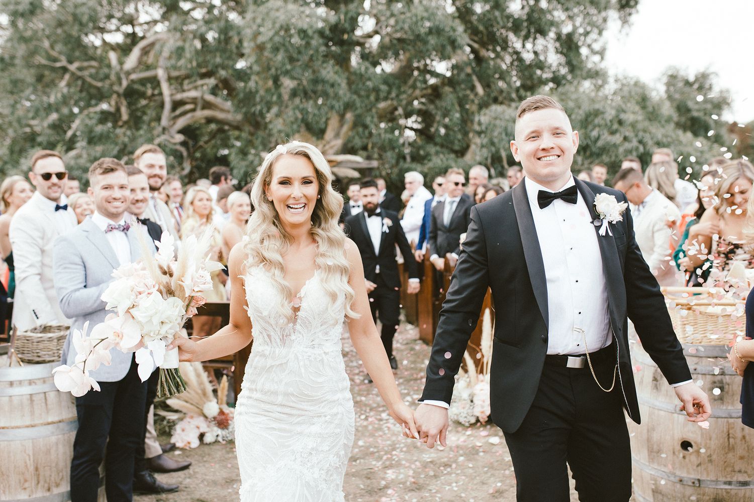 Wedding celebration with confetti toss among guests in garden setting.