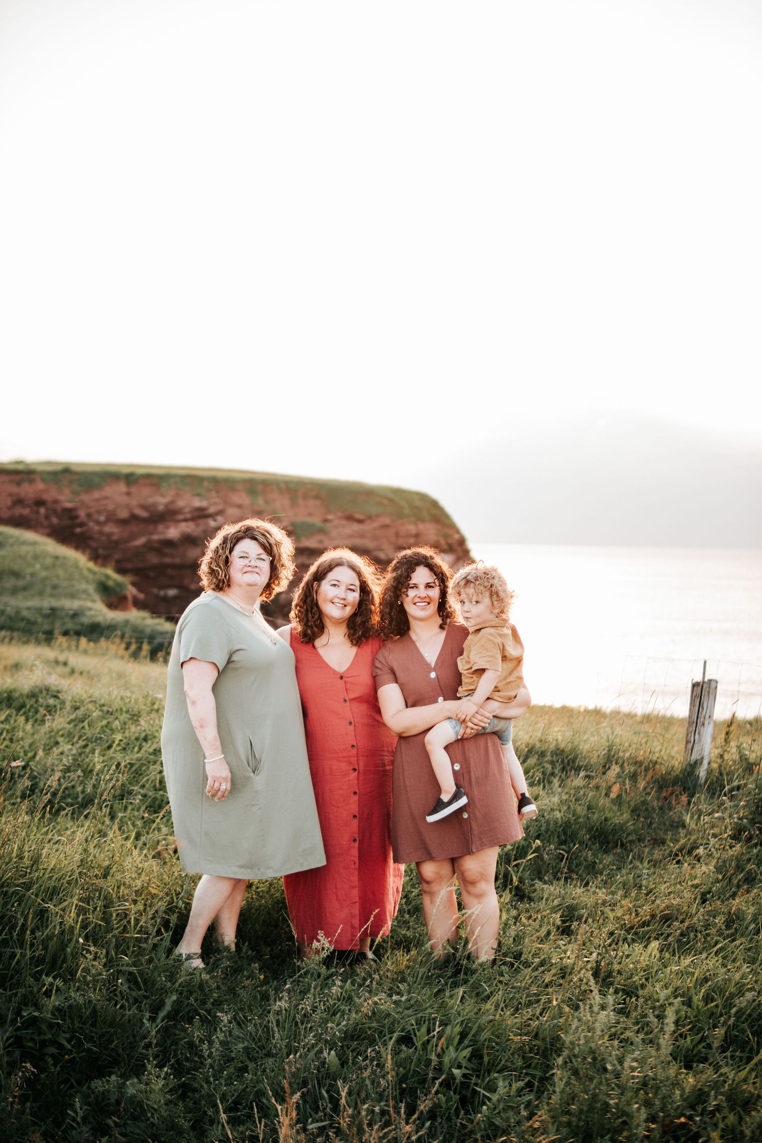 Group of friends posing together on a scenic coastal cliff at sunset.