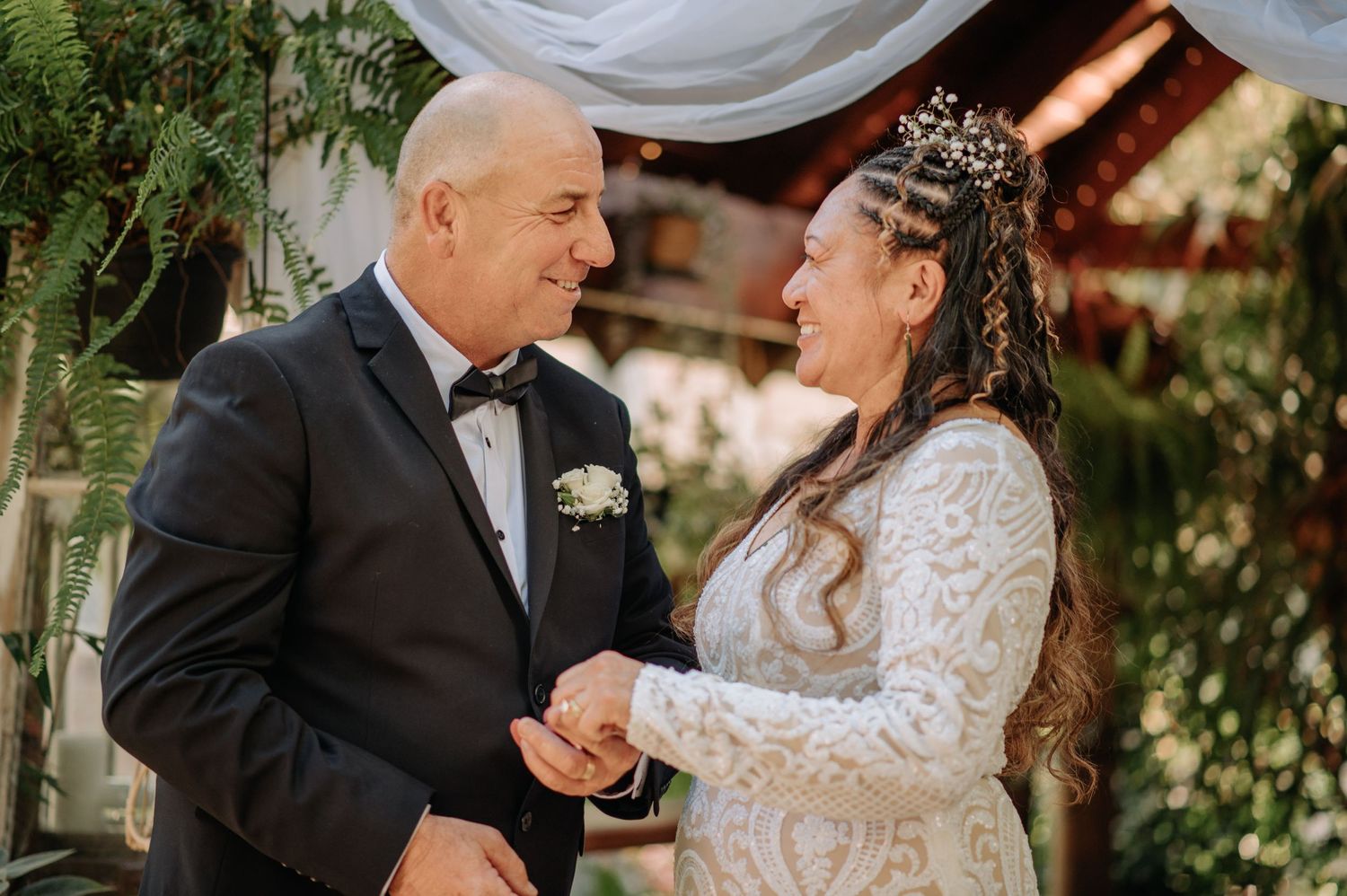 A touching moment during a wedding ceremony under a decorated gazebo.