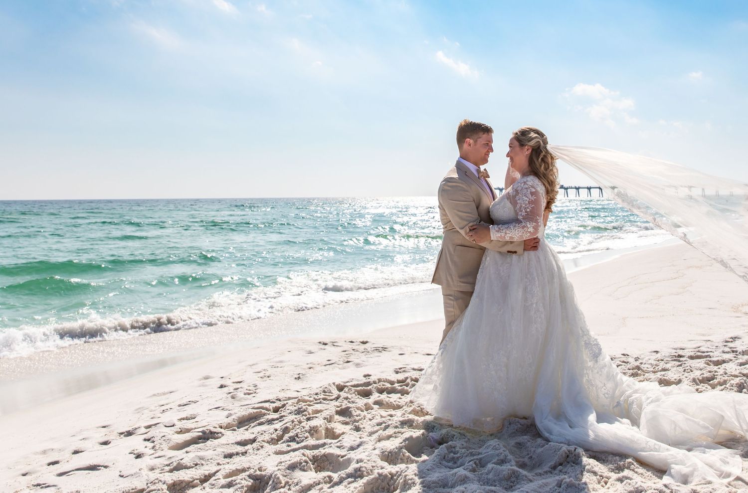 A couple shares a romantic moment on a white sandy beach with turquoise waters and clear blue skies.