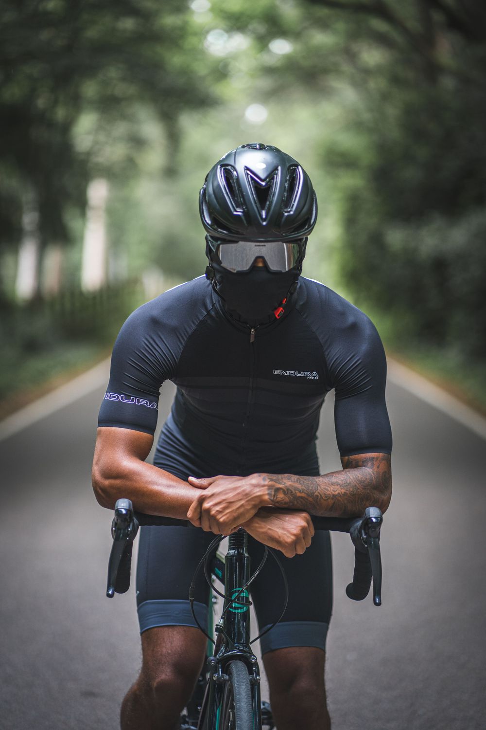 Close-up of cyclist in dark clothing and protective gear on a forest road.