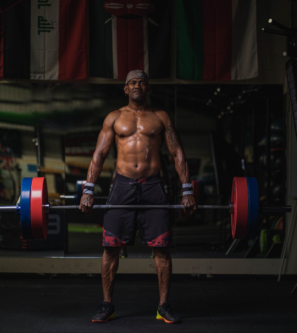 Athletic person performing deadlift with red and blue weighted barbell in gym.