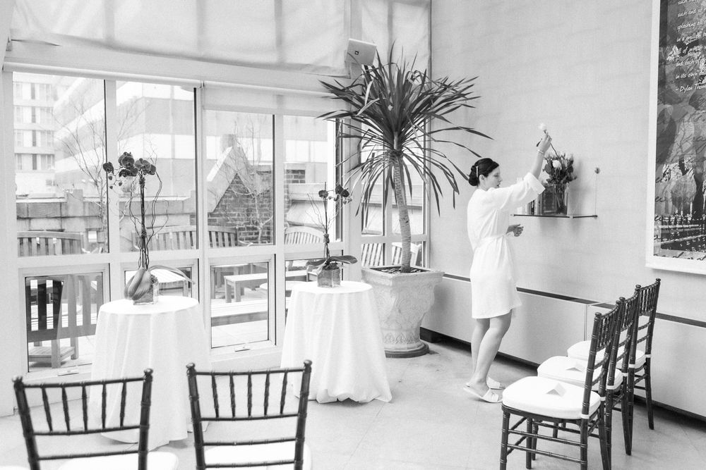 a black and white view of a woman decorating a wedding ceremony room, photo by NYC elopement Paula Ortiz