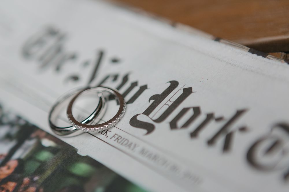 wedding rings on top of The New York Times front page paper, photo by NYC wedding photographer Paula Ortiz